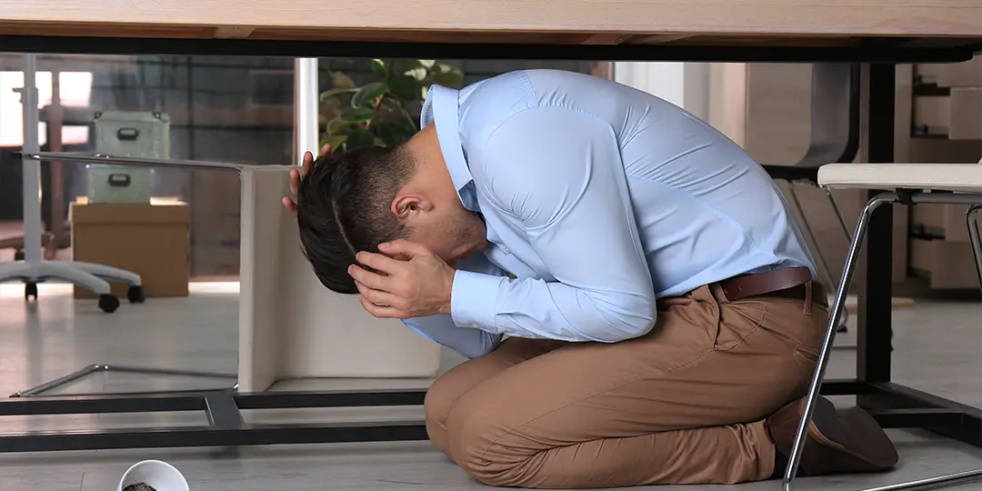 Man hiding under desk during an ASI