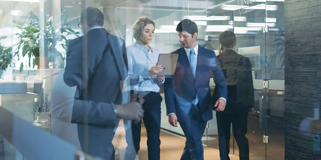 office setting staff walking through hallway talking